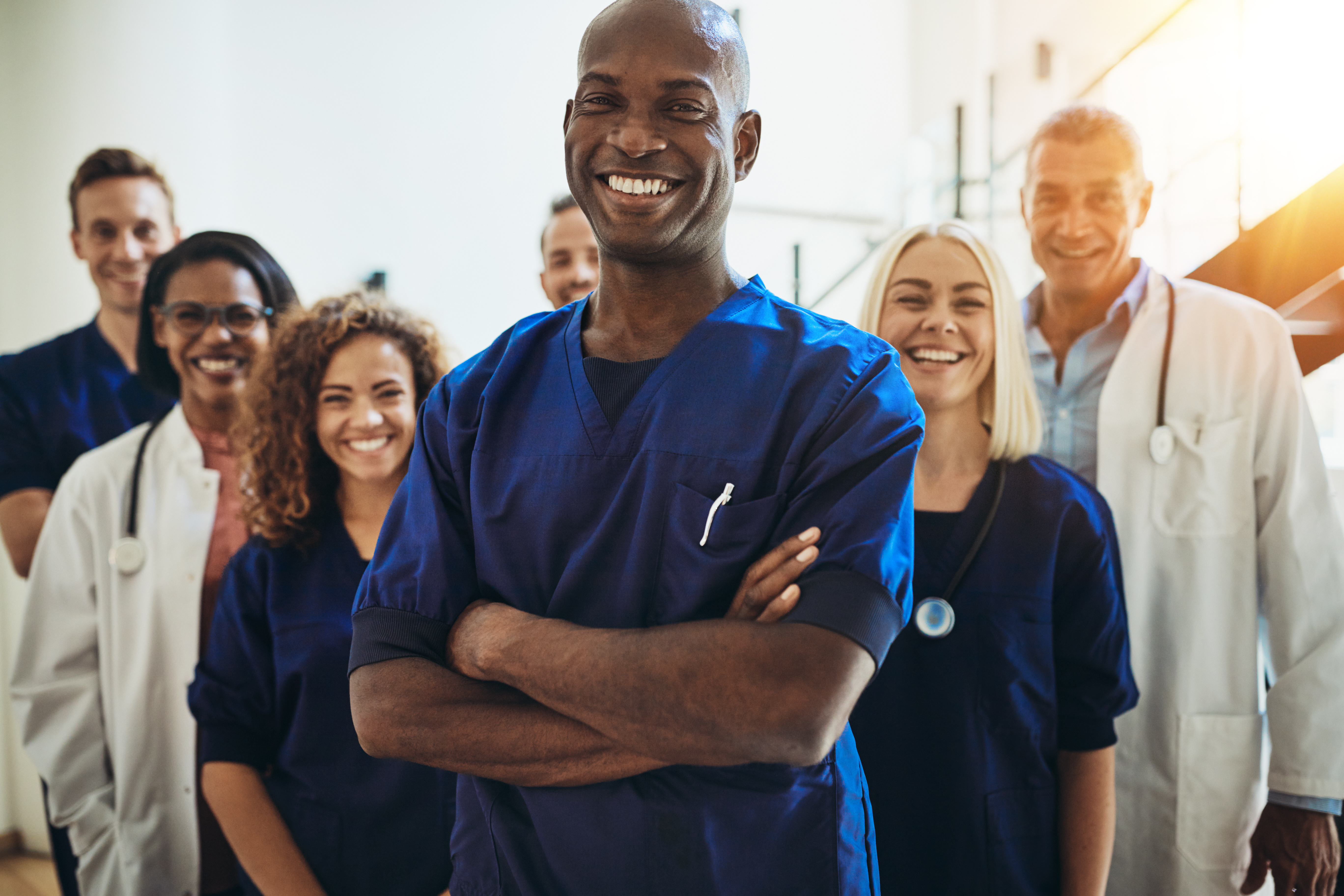 Smiling black doctor standing in a room with other healthcare staff