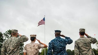 Four U.S. Service Members saluting the American flag