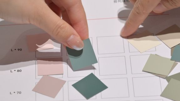 Farbseminare und Workshops | RAL FARBEN Nahaufnahme von Händen, die Farbchips in ein Raster nach Helligkeit einsortieren.Colour seminars and workshops | RAL COLOURSClose-up of hands sorting colour chips into a grid according to lightness.