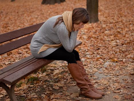 Eine Frau sitzt traurig auf einer Bank in einem Park im Herbst. Quelle: © drubig-photo / Fotolia