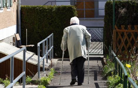 Rückansicht einer älteren Frau mit Gehhilfen. Quelle: © Günter Havlena / pixelio.de