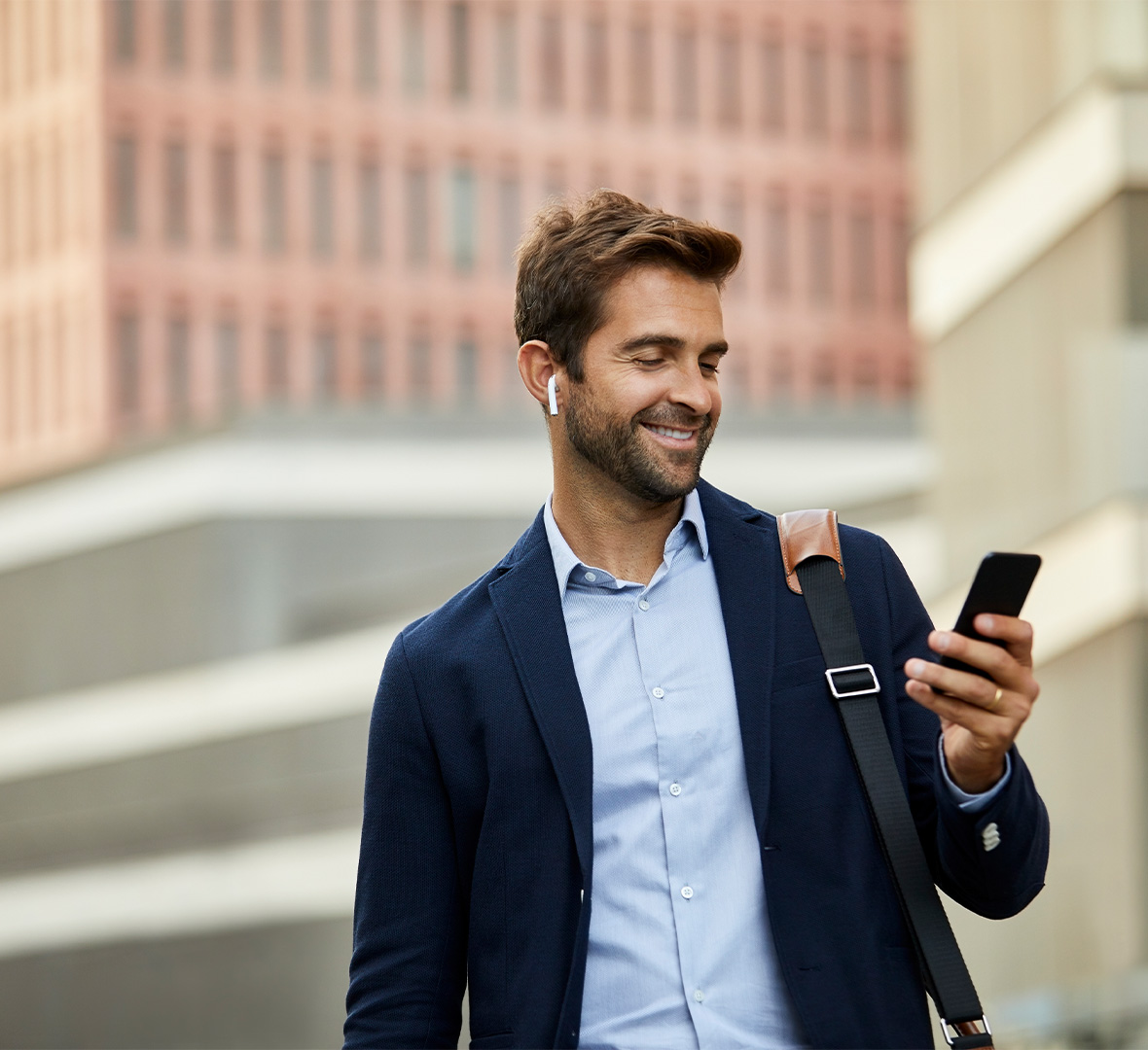 homem de negócios a olhar para o telemóvel e com uns fones nos ouvidos