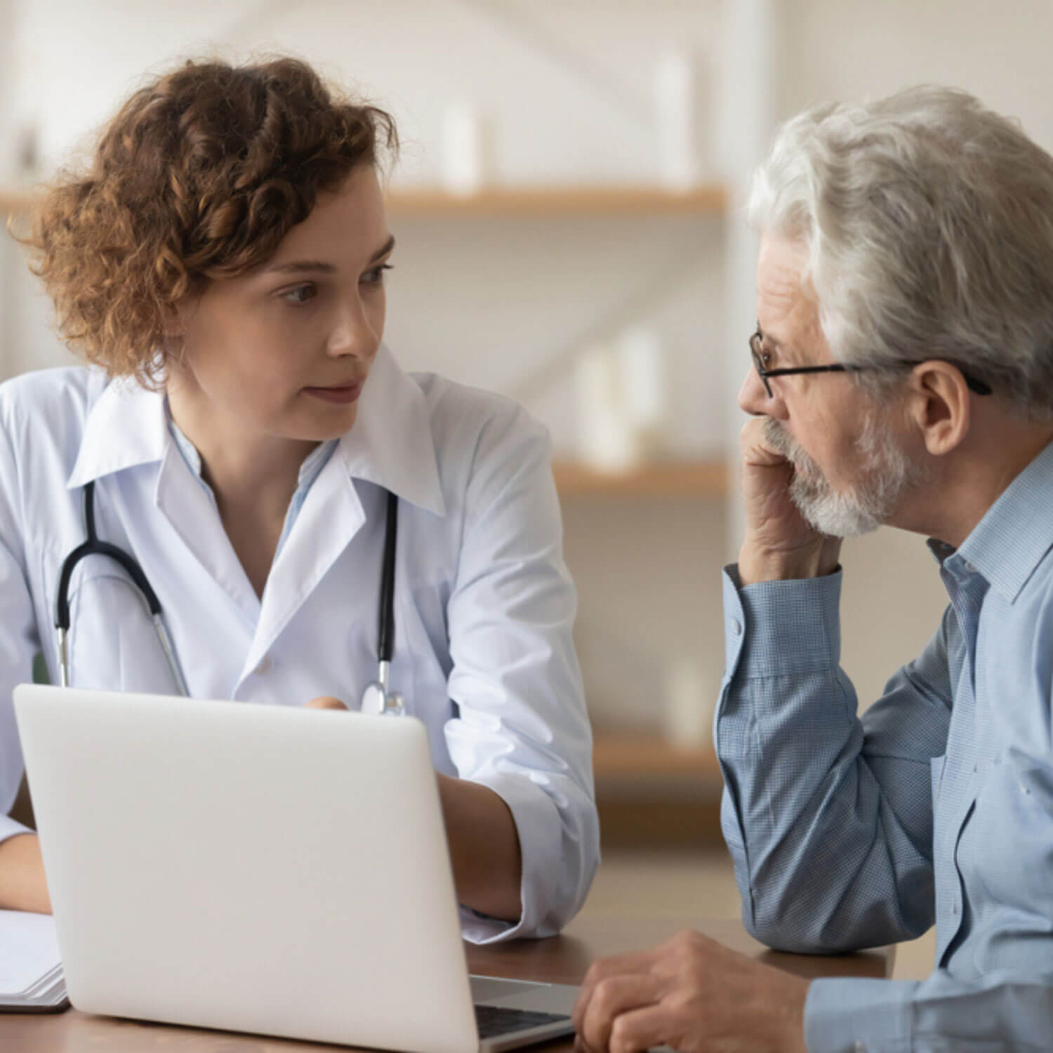 Una proveedora de cuidados de salud hablando con un paciente sentados frente a un computador.