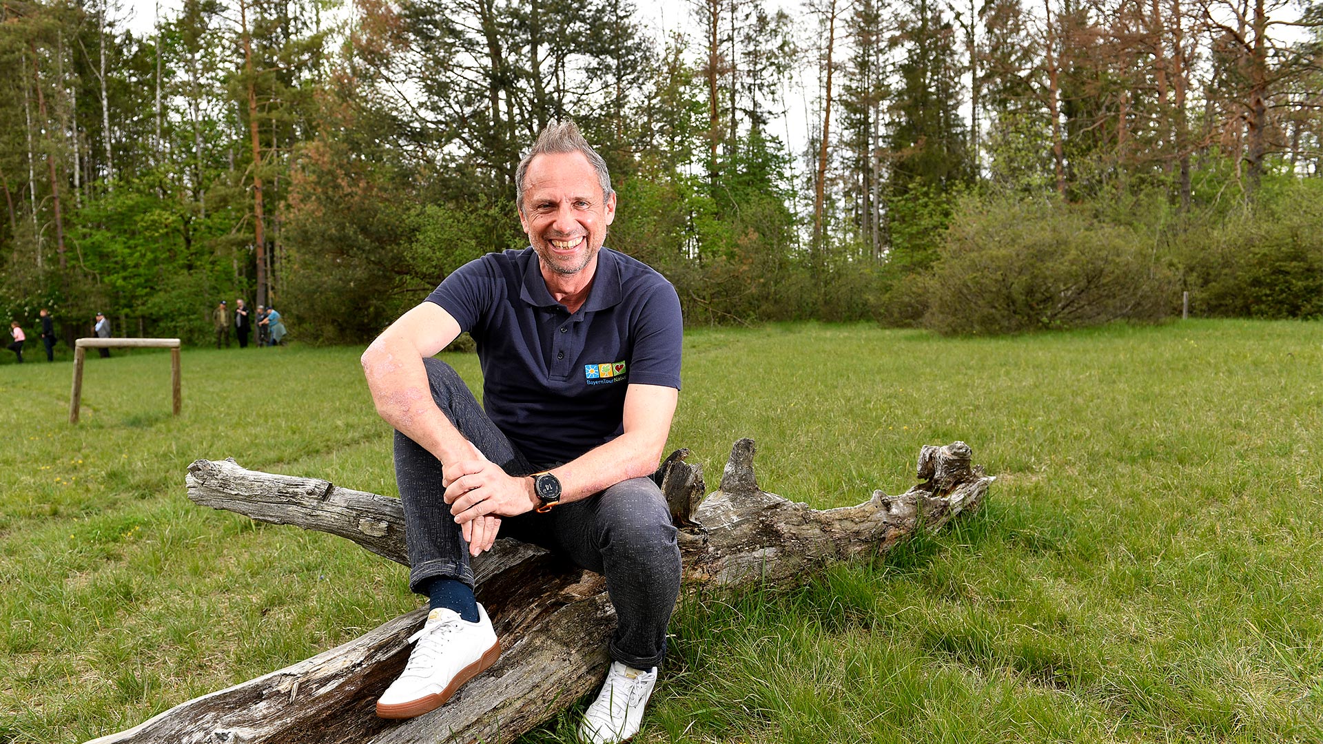 Minister Glauber auf Baumstamm im Nationalpark