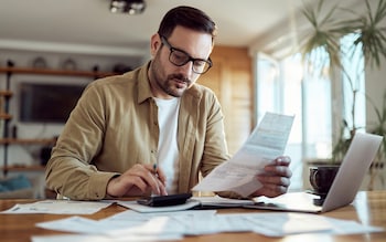 Young man using calculator while working on his financial plans 