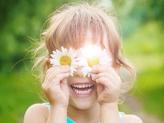 Mädchen hält Blumen vor die Augen.