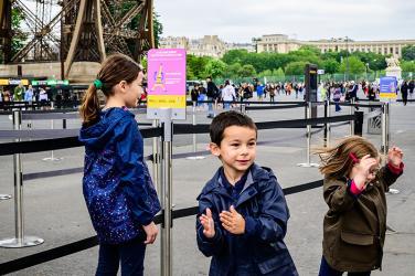 Panneau de défi sportif et enfants dans une file d'attente du parvis de la tour Eiffel