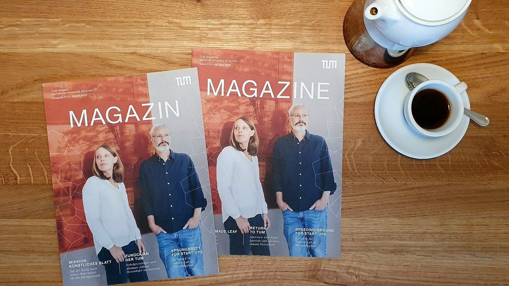  Two issues of the new magazine of the Technical University of Munich (TUM) on a wooden table, with coffee crockery next to it