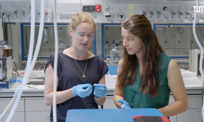 Physics student Nina Miller stands in a laboratory and has a researcher explain a scientific fact to her.