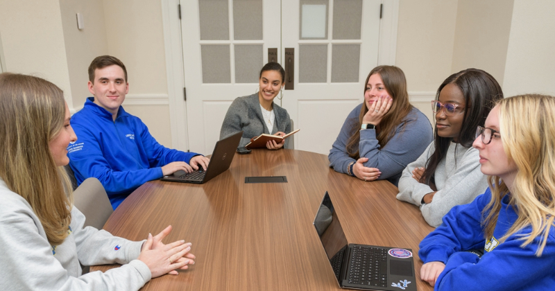 Students sitting at table in Warner Hall talking