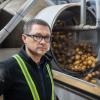 A man stands next to a potato sorting machine.