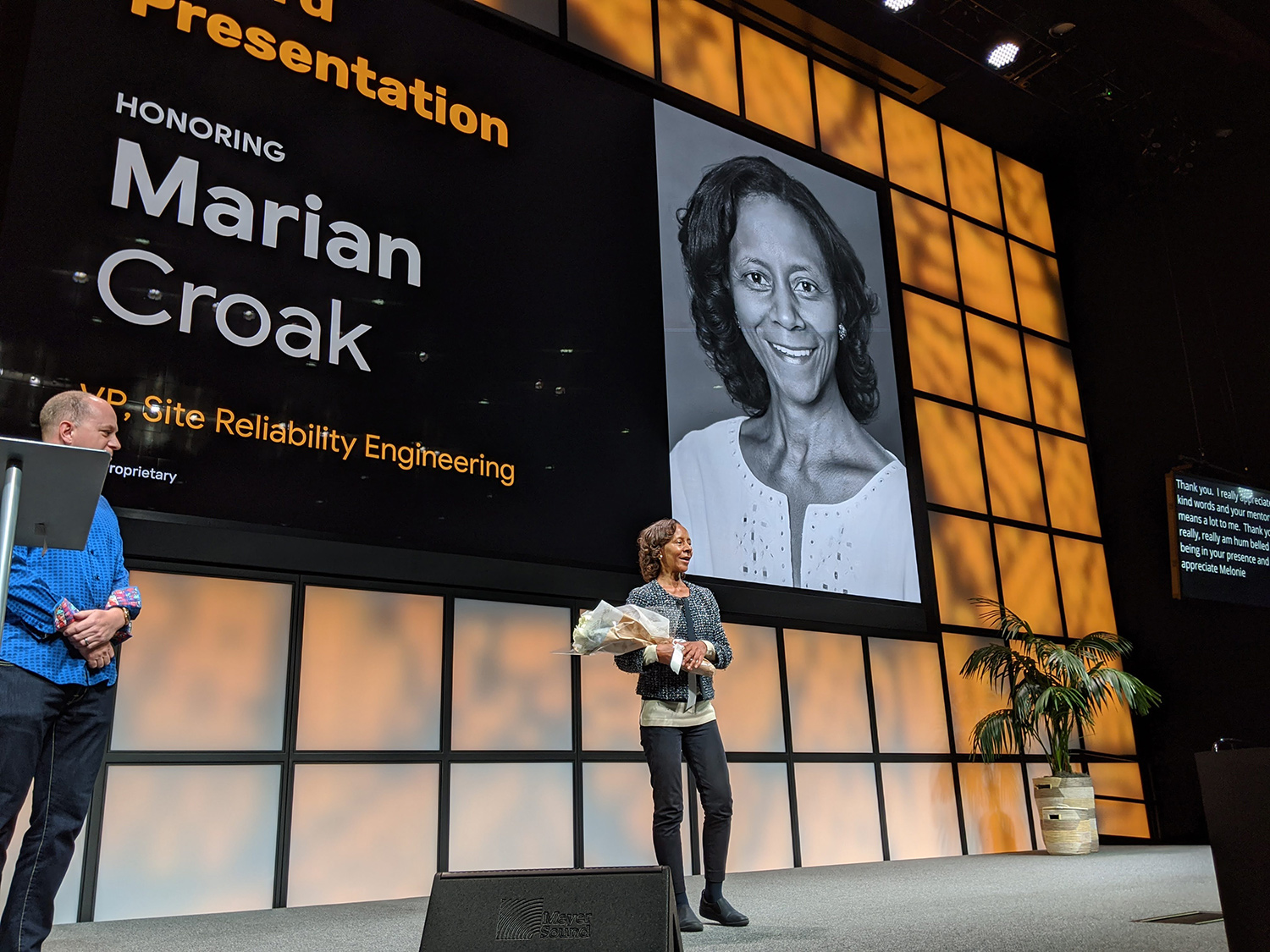 Marian Croak holds flowers while being honored on stage