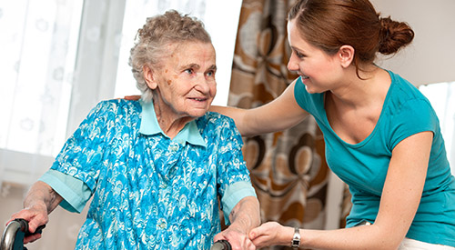 An elderly woman with a walker being assisted by a middle aged lady