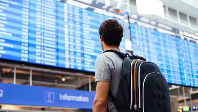 Person mit Rucksack steht am Flughafen vor der Fluganzeigetafel; Copyright Panthermedia; Link zum Artikel