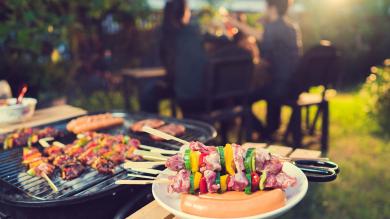 Grill mit Fleisch und Menschengruppe im Hintergrund