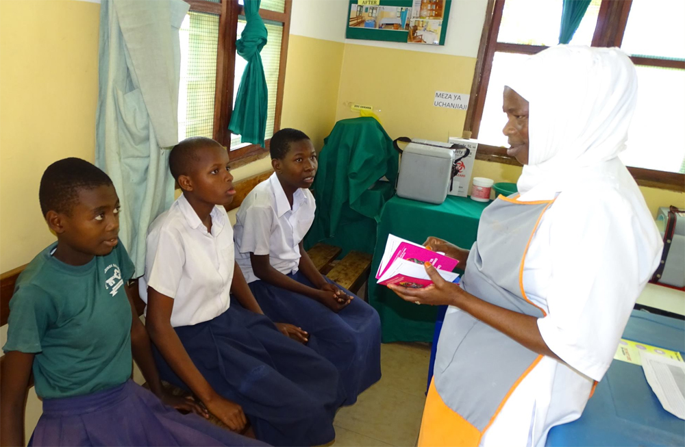 Health care worker interacting with Tanzanian girls before vaccination