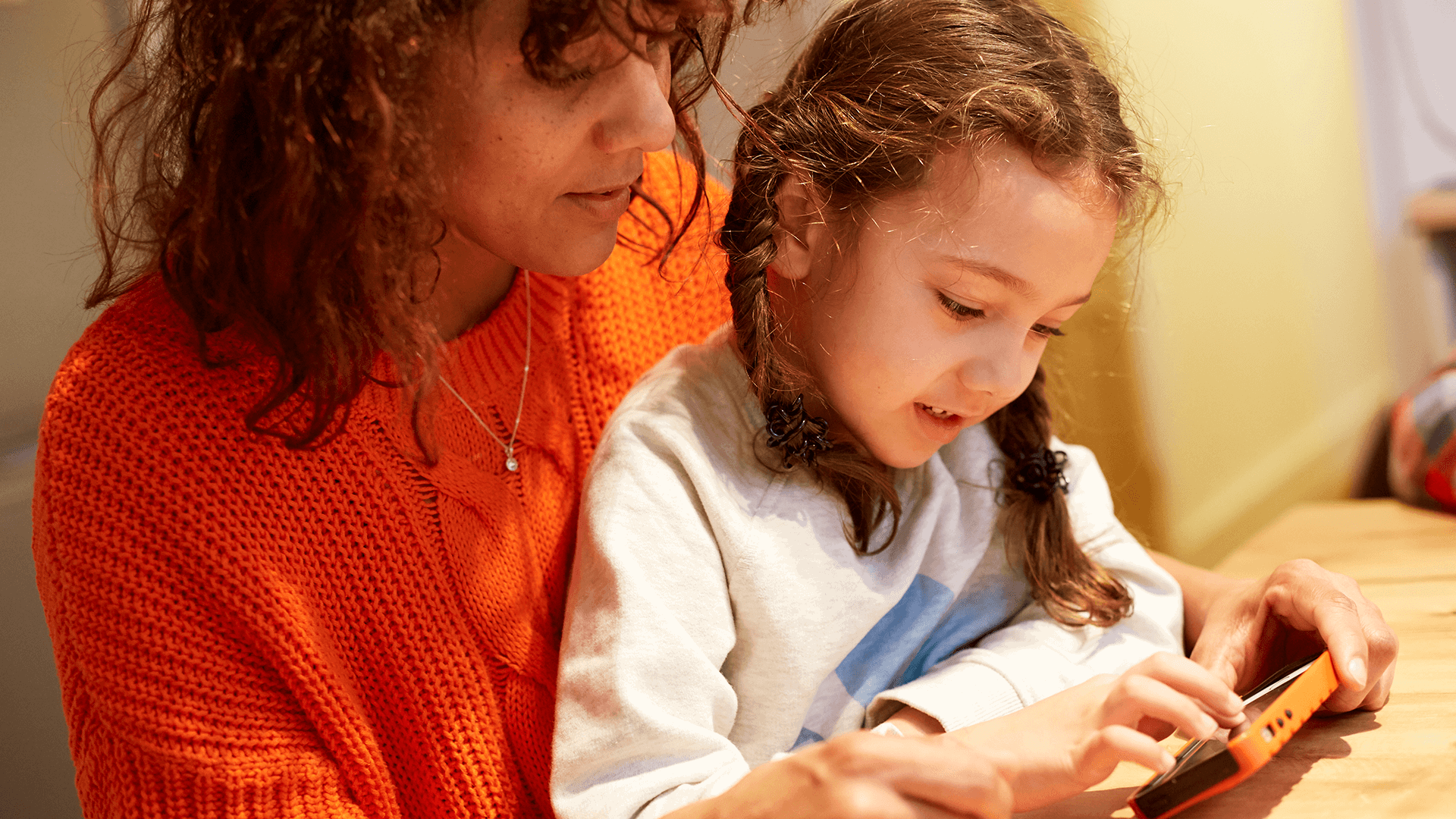 Parent and child looking at a mobile phone together.