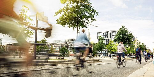 Radweg mit Radfahrer*innen in einem Neubaugebiet