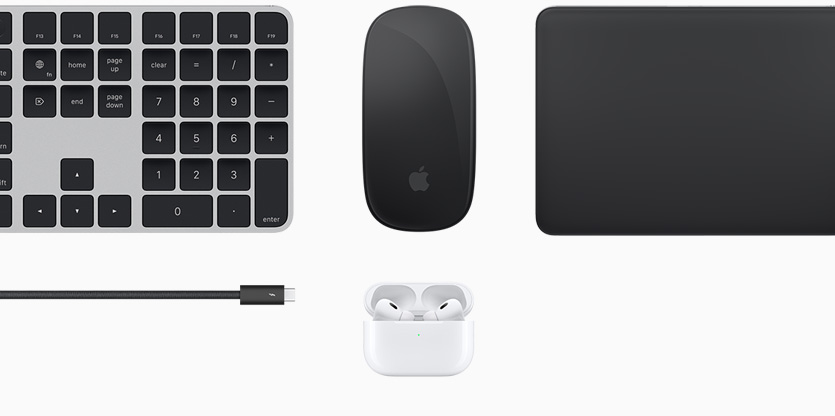 Various Mac accessories, including a black Magic Keyboard with Touch ID, a black Magic Mouse, a black Magic Trackpad, a black accessories cord and white AirPods inside an open white charging case.